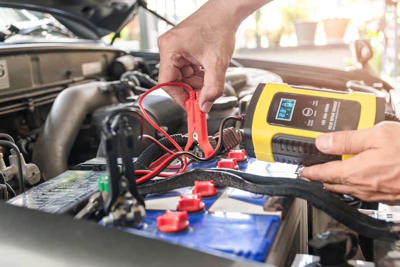 Mechanic charging a car battery on-site during a breakdown call