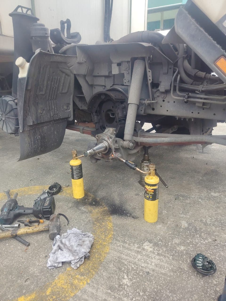Lorry wheel removed, on-site brake and suspension repair with tools and gas torches